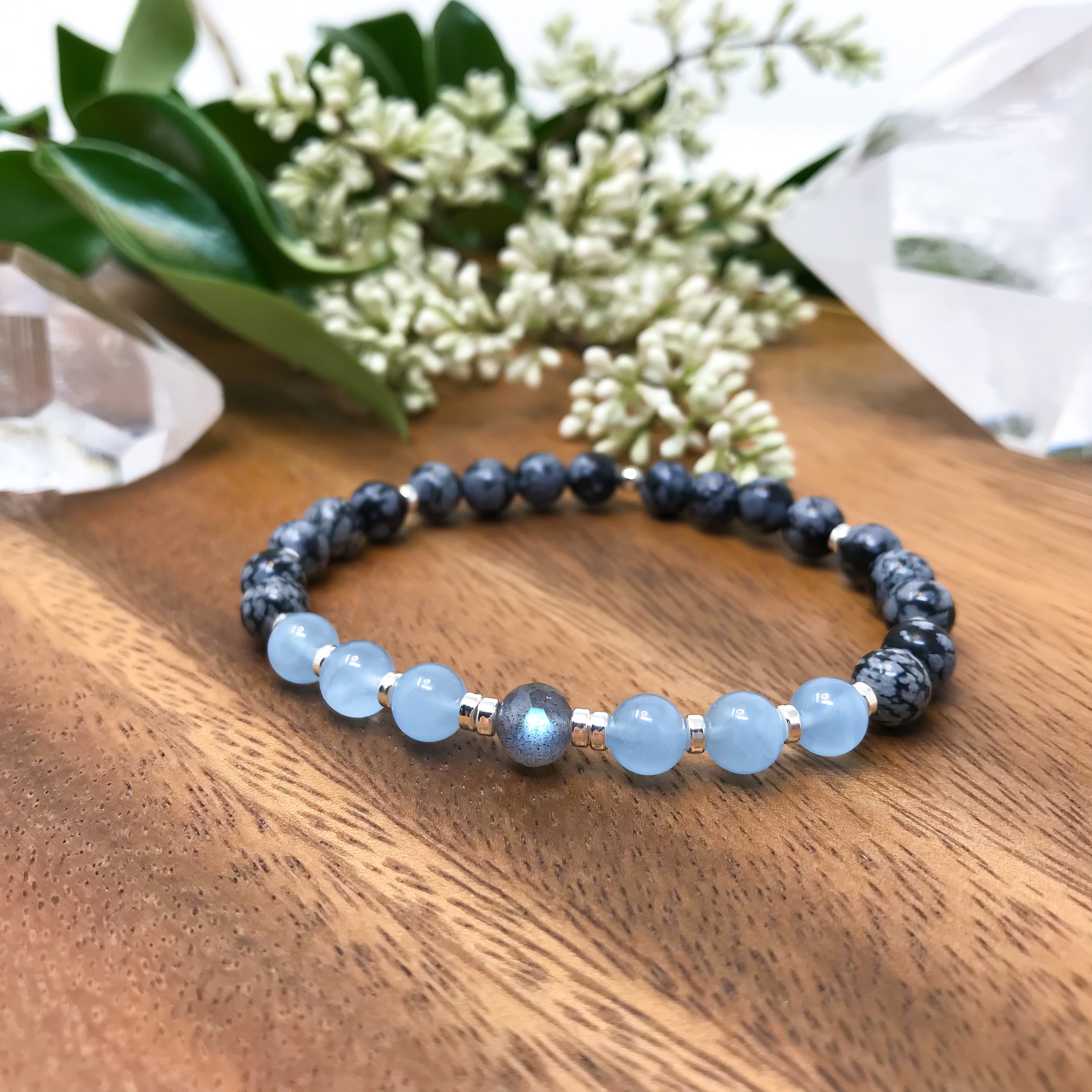 A crystal healing mala bracelet with black Obsidian with snowflake like pattern, light blue Aquamarine and a faceted gray Labradorite focal bead with blue flash. Choose sterling silver or gold accents. Yoga jewelry.
