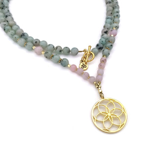 A beaded mala necklace featuring light green sesame Jasper and pink opal gemstones with small gold spacer beads and a gold-tone flower of life pendant, displayed on a clean white background.